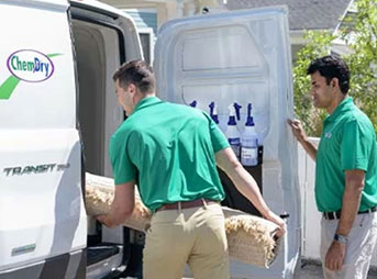 technicians loading area rug into van for cleaning